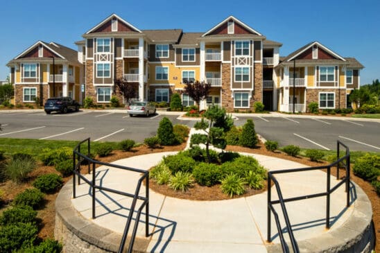 Modern apartment complex with landscaped entrance and parking lot
