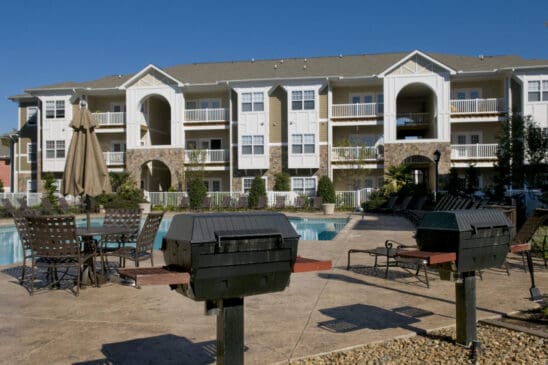 Apartment complex pool area with grills and patio seating