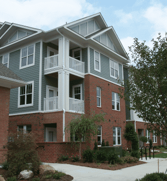 Three-story brick and siding apartment building with balconies