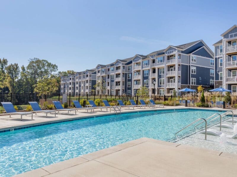 Modern apartment complex with outdoor pool and loungers