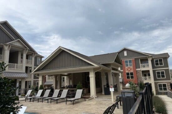 Apartment complex courtyard with poolside lounge chairs and pavilion