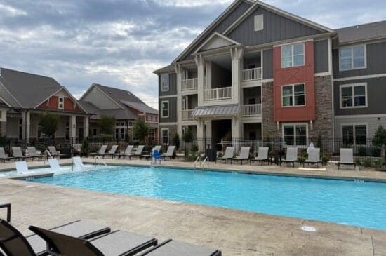 Apartment complex with outdoor pool and lounge chairs