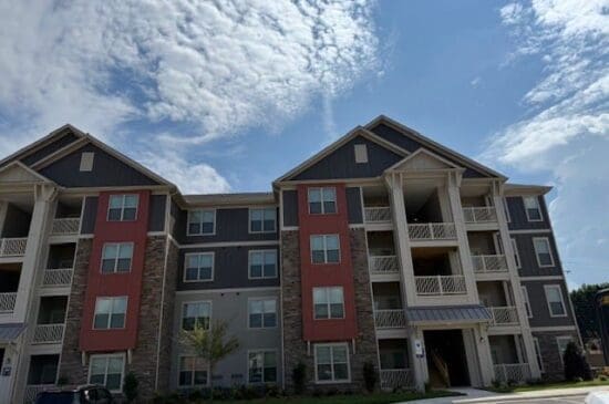 Three-story apartment building with balconies under blue sky