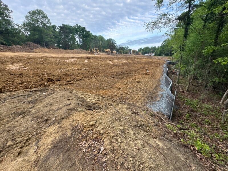 Cleared construction site with bulldozers and silt fence